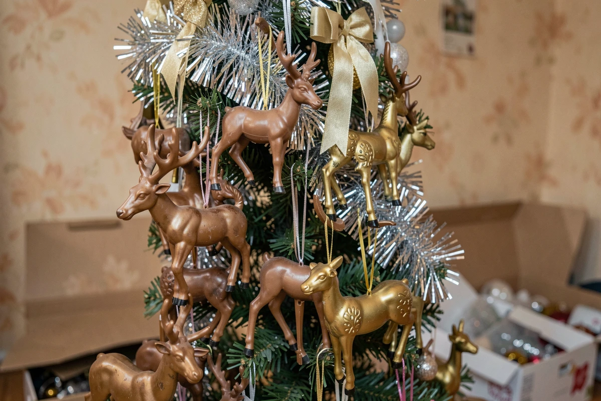 Gros plan sur une branche de sapin surchargée de décorations de rennes en plastique bon marché et de guirlandes enchevêtrées, exemple d'erreurs d'aménagement de sapin de Noël
